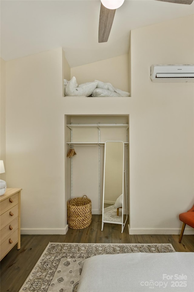 bedroom featuring wood finished floors, a wall mounted air conditioner, and baseboards