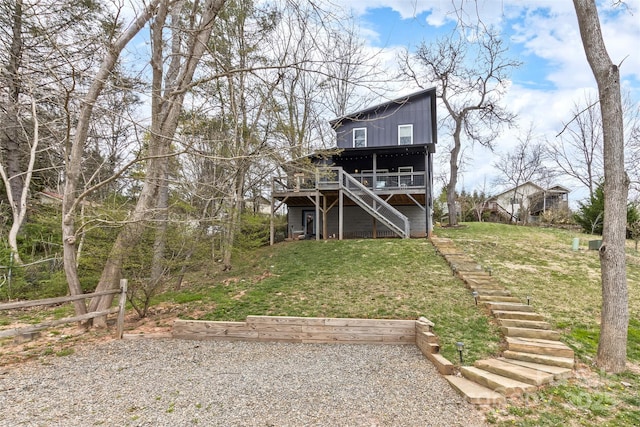 back of property with a lawn, a wooden deck, and stairs