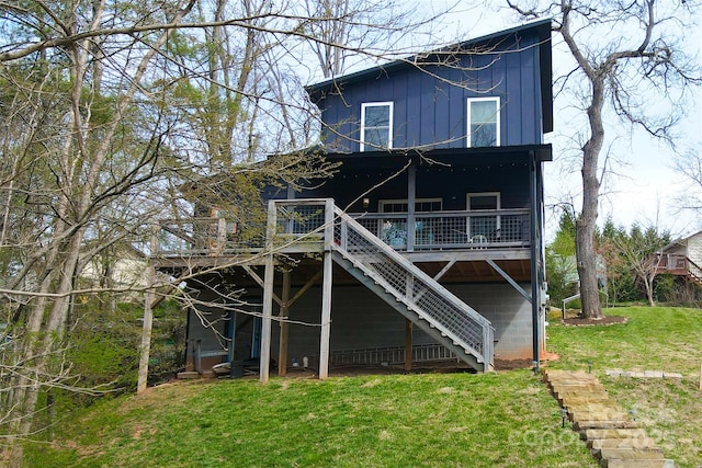 back of property with stairway, a wooden deck, and a lawn
