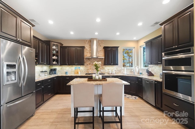 226 Hermance Ln, Mooresville, NC 28117 - kitchen with stainless steel appliances, wall chimney exhaust hood, a kitchen island, light wood-type flooring, and recessed lighting