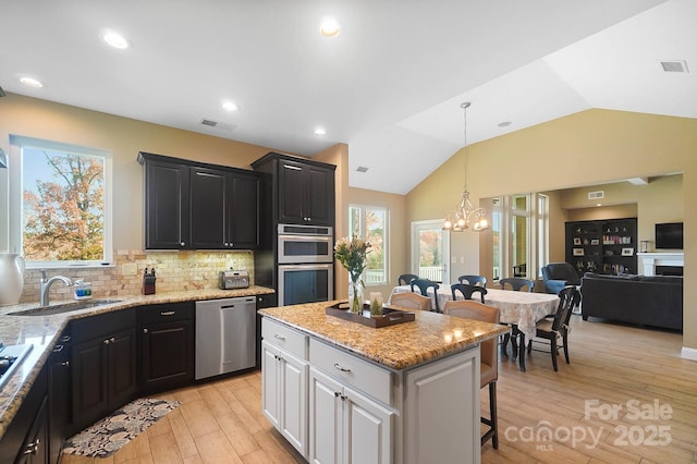 226 Hermance Ln, Mooresville, NC 28117 - kitchen with stainless steel appliances, a kitchen breakfast bar, dark cabinets, light wood-style floors, and a sink