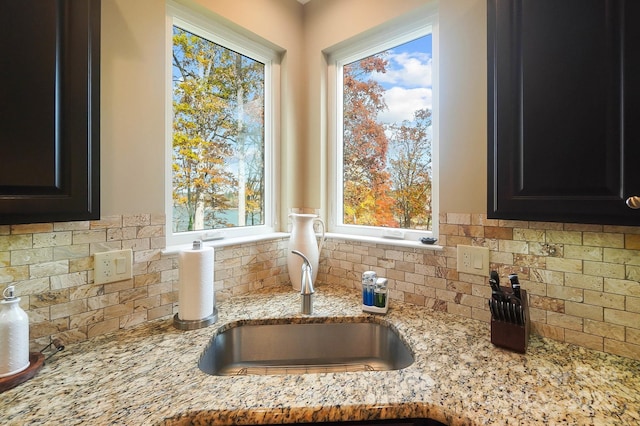 226 Hermance Ln, Mooresville, NC 28117 - kitchen view of decorative backsplash, a sink, light stone counters, and dark cabinets