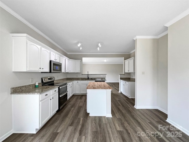 kitchen featuring dark wood-type flooring, butcher block countertops, a center island, appliances with stainless steel finishes, and white cabinets