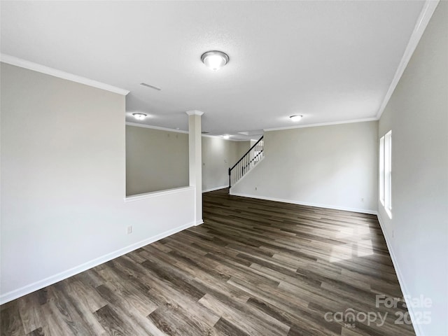 empty room featuring crown molding, baseboards, and dark wood-style flooring