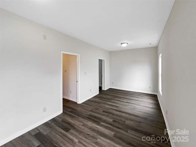 spare room featuring dark wood-style floors and baseboards