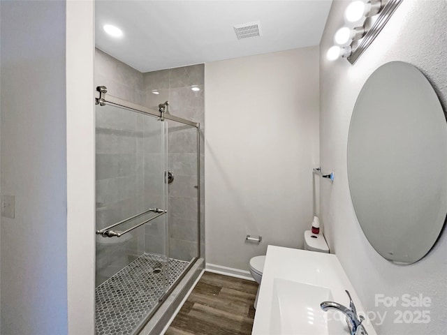 full bath featuring toilet, wood finished floors, visible vents, and a stall shower