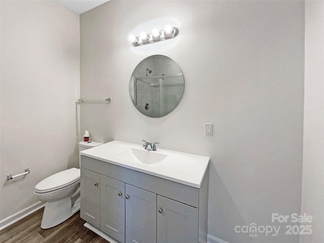 bathroom featuring vanity, toilet, wood finished floors, and walk in shower