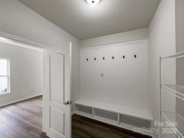 mudroom with baseboards, a textured ceiling, and wood finished floors