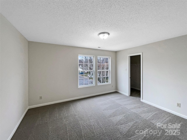 spare room featuring baseboards, carpet, and a textured ceiling