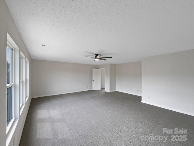 spare room with visible vents, a ceiling fan, a textured ceiling, dark carpet, and baseboards