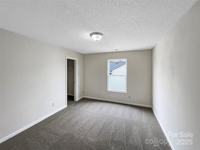 empty room featuring baseboards, carpet floors, and a textured ceiling