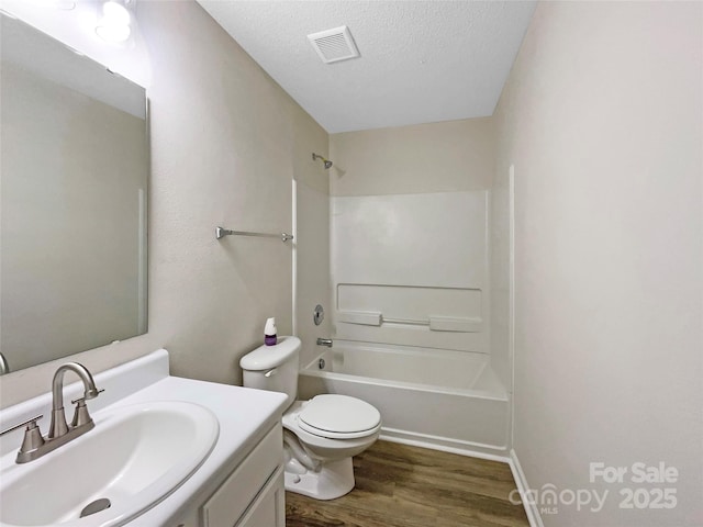 bathroom with visible vents, toilet, a textured ceiling, wood finished floors, and vanity