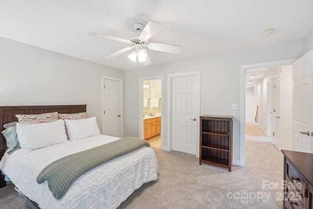 bedroom with ensuite bath, light colored carpet, a sink, and ceiling fan