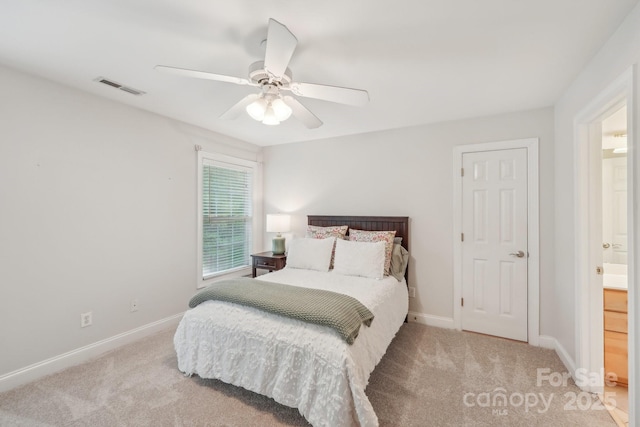 carpeted bedroom with ensuite bathroom, baseboards, a ceiling fan, and visible vents