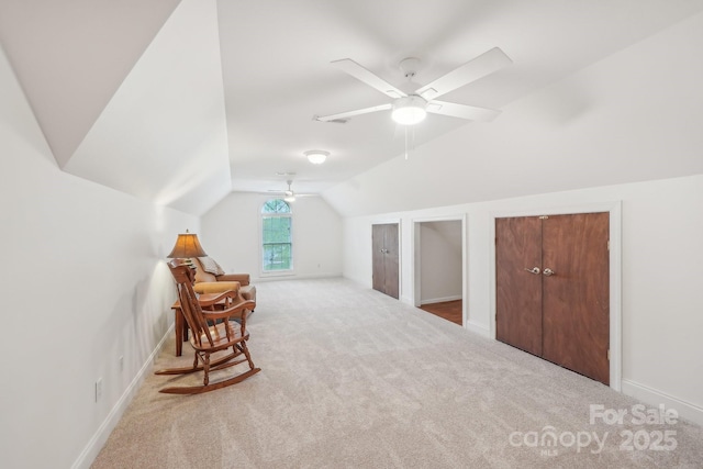sitting room with ceiling fan, carpet floors, baseboards, and lofted ceiling
