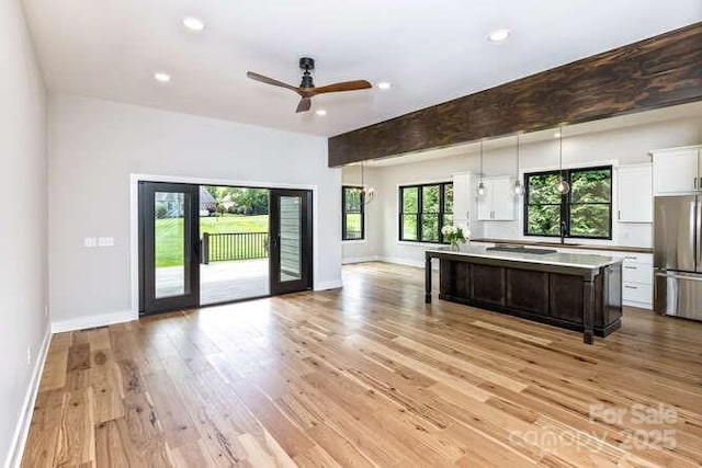 kitchen featuring freestanding refrigerator, open floor plan, a center island, white cabinets, and light wood finished floors