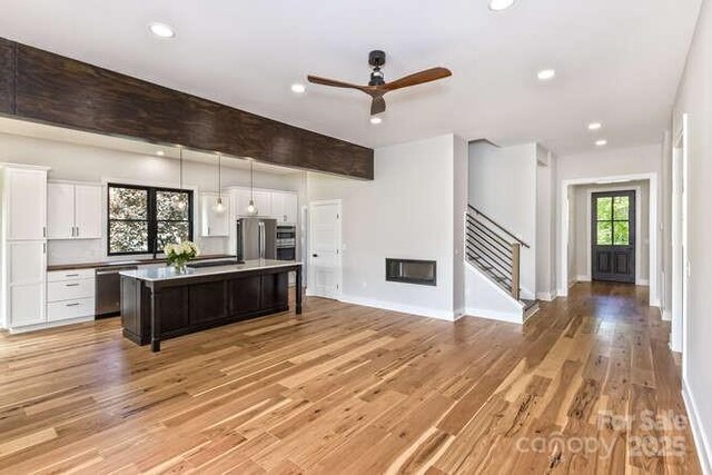 kitchen featuring white cabinets, ceiling fan, appliances with stainless steel finishes, a center island, and open floor plan