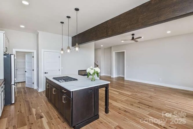 kitchen with gas cooktop, a kitchen island, pendant lighting, freestanding refrigerator, and light wood-style floors
