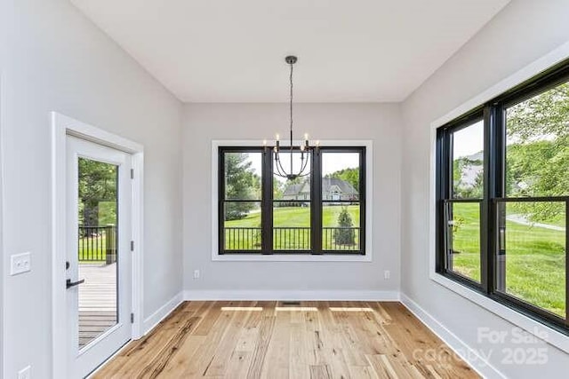 unfurnished dining area with an inviting chandelier, light wood-style flooring, baseboards, and plenty of natural light