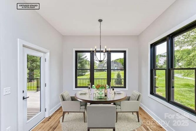 dining space featuring light wood-style floors, baseboards, a chandelier, and a wealth of natural light