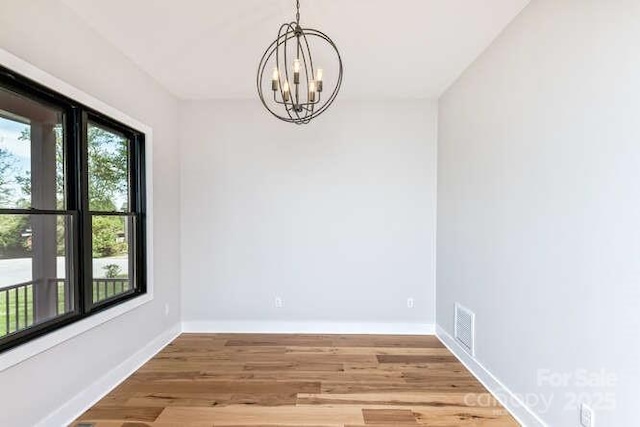 unfurnished dining area featuring an inviting chandelier, baseboards, light wood-style floors, and visible vents
