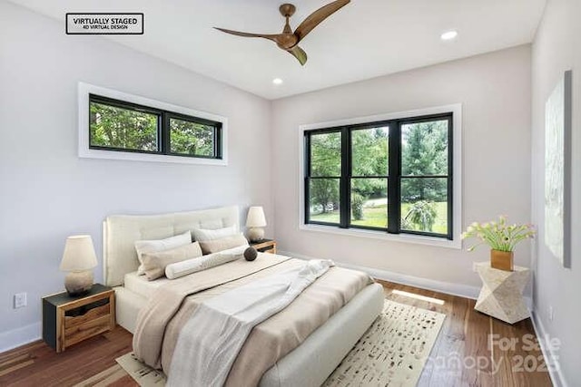 bedroom with baseboards, multiple windows, and wood finished floors