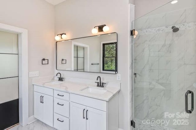 full bathroom featuring double vanity, a sink, marble finish floor, and a stall shower