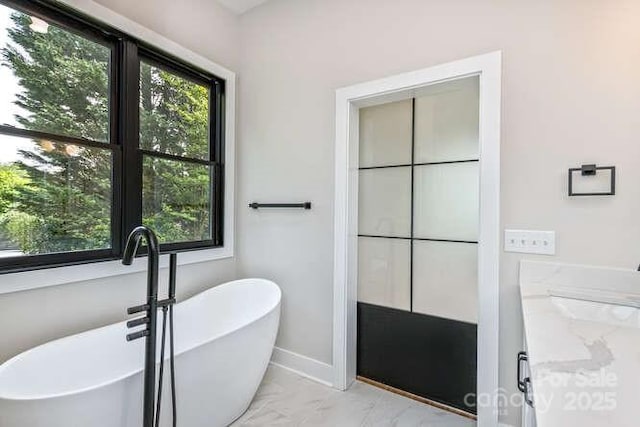 bathroom with a freestanding tub and marble finish floor