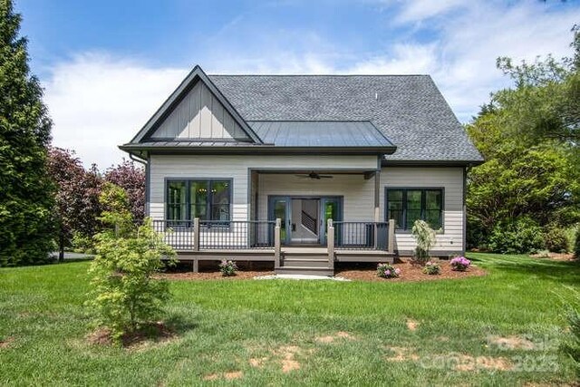 rear view of property featuring a lawn, a ceiling fan, board and batten siding, and a standing seam roof