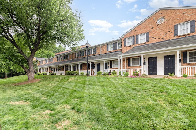 view of front facade with a front lawn, covered porch, and brick siding
