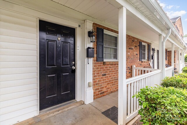 property entrance featuring brick siding and a porch