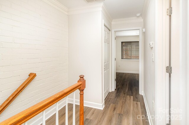 hall with an upstairs landing, wood finished floors, crown molding, and baseboards