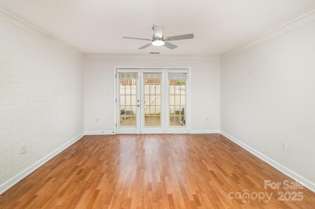 spare room featuring baseboards, light wood-style flooring, ceiling fan, and brick wall