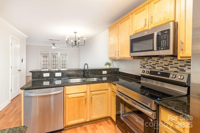 kitchen with a sink, stainless steel appliances, visible vents, a peninsula, and ornamental molding