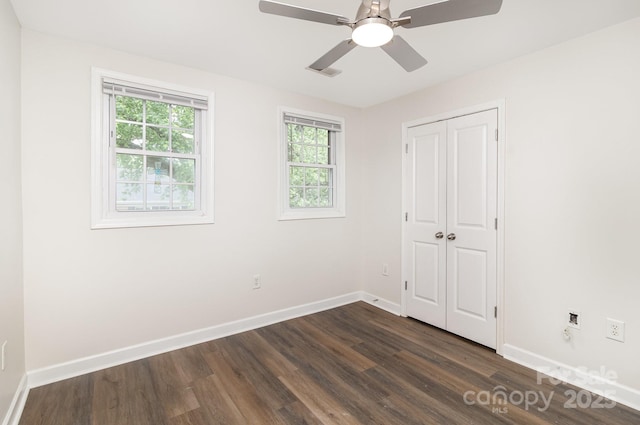 unfurnished bedroom with dark wood-style flooring, a closet, a ceiling fan, visible vents, and baseboards