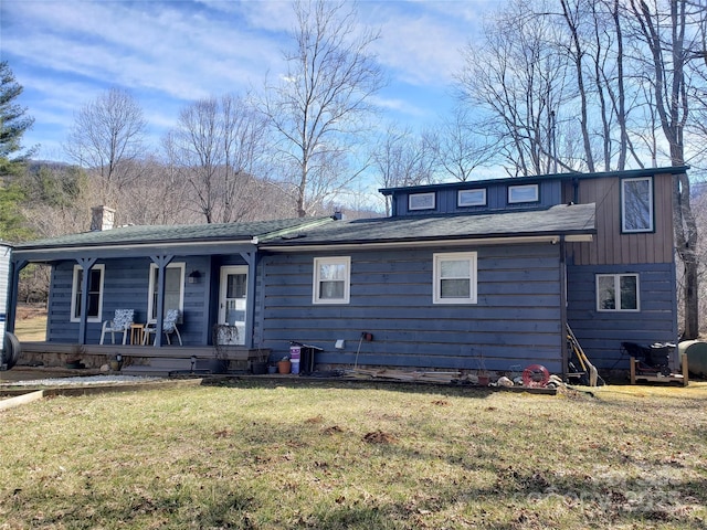 view of front of home featuring covered porch, a chimney, and a front yard