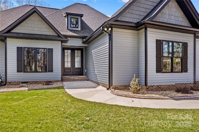 exterior space featuring french doors, a front lawn, and roof with shingles