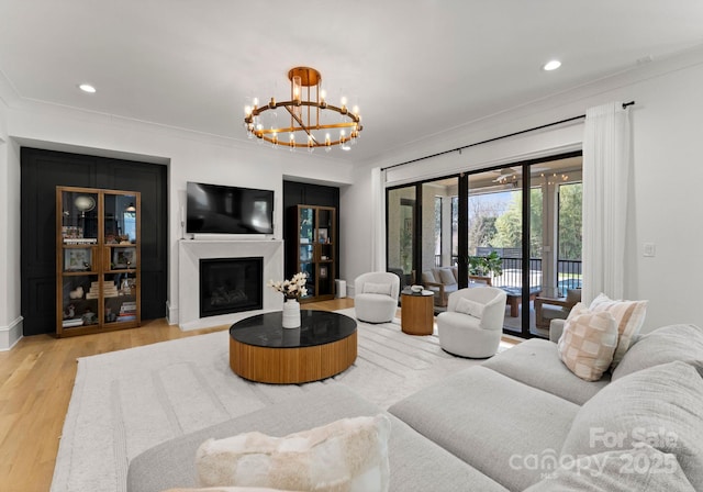 300 Mammoth Oaks Dr, Charlotte, NC 28270 - living area featuring a chandelier, crown molding, wood finished floors, a glass covered fireplace, and recessed lighting