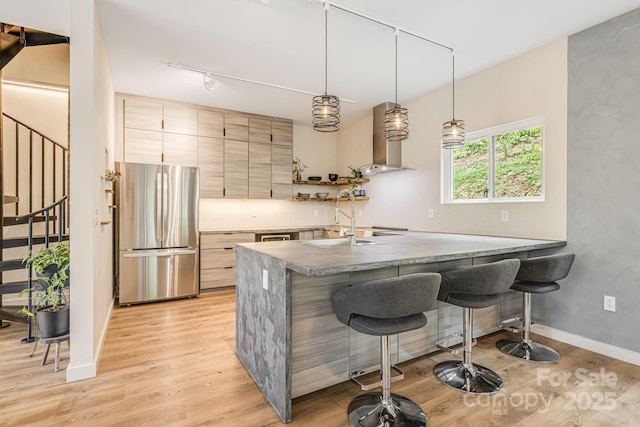 47 Webb Cove Rd, Asheville, NC 28804 - kitchen with wall chimney exhaust hood, light wood-type flooring, freestanding refrigerator, and a sink