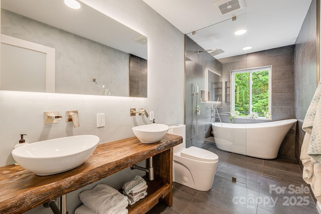47 Webb Cove Rd, Asheville, NC 28804 - bathroom featuring visible vents, double sink, tile walls, a soaking tub, and walk in shower