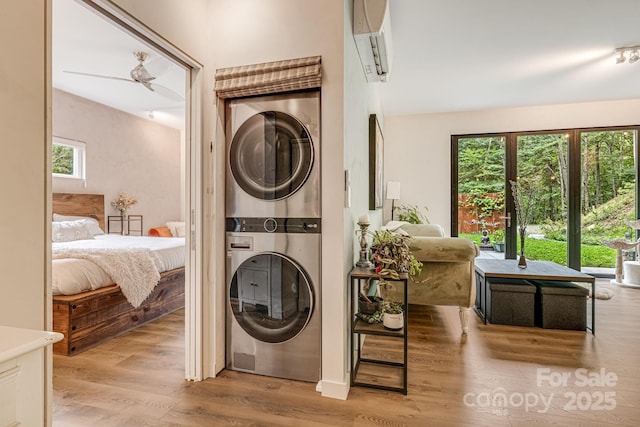 47 Webb Cove Rd, Asheville, NC 28804 - clothes washing area with a ceiling fan, a wall unit AC, light wood-style floors, stacked washer / dryer, and laundry area