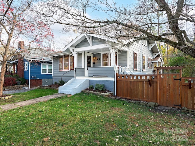 view of front of property with a porch, a chimney, a front lawn, and fence
