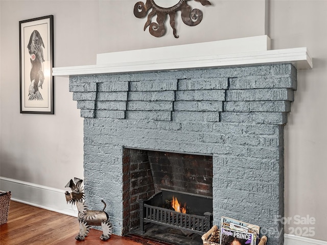 room details with baseboards, a brick fireplace, and wood finished floors
