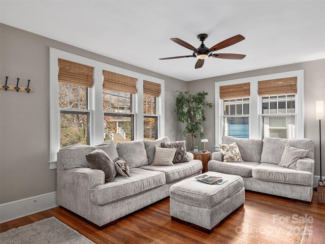 living room with dark wood finished floors, a healthy amount of sunlight, baseboards, and ceiling fan