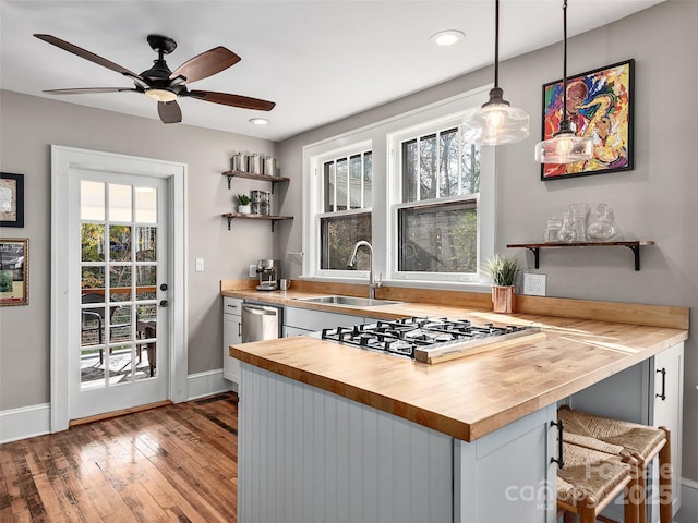 kitchen with a sink, wooden counters, stovetop, hardwood / wood-style flooring, and open shelves