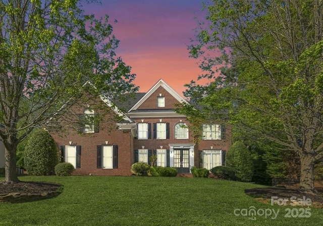view of front of house featuring a front lawn, brick siding, and french doors