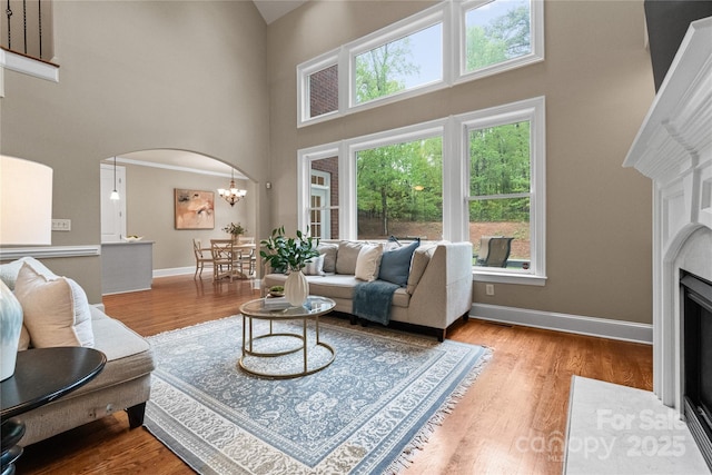 living room with arched walkways, a high ceiling, wood finished floors, and baseboards