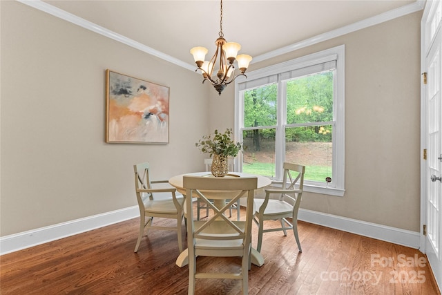 dining area with an inviting chandelier, crown molding, wood finished floors, and baseboards