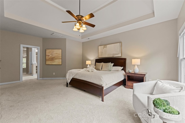 bedroom with visible vents, baseboards, a tray ceiling, and light colored carpet