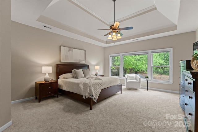 bedroom with ceiling fan, a tray ceiling, baseboards, carpet flooring, and visible vents